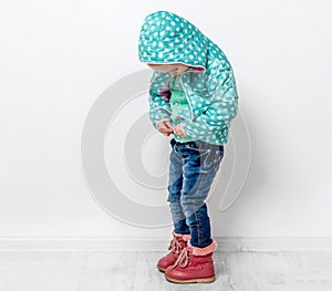 Little girl fastening her blue jacket