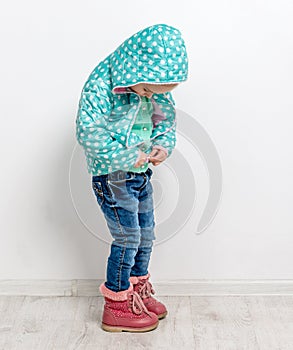 Little girl fastening her blue jacket