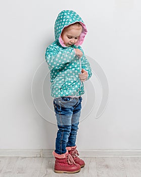 Little girl fastening her blue jacket