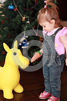 Little girl feeding carrot toy donkey