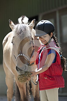 Little girl feeding her favorite horse some hay