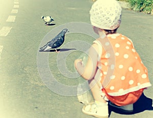 Little girl feeding pigeons.