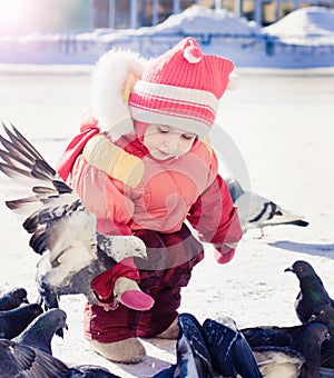 Little girl feeding pigeons in winter