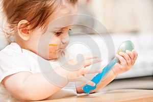 Little girl feeding from a spoon on blue chair.