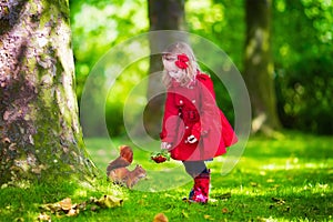 Little girl feeding a squirrel in autumn park