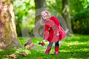 Little girl feeding a squirrel in autumn park