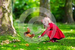 Little girl feeding a squirrel in autumn park