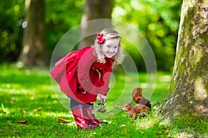 Little girl feeding a squirrel in autumn park