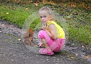 Little girl feeding squirrel with nuts