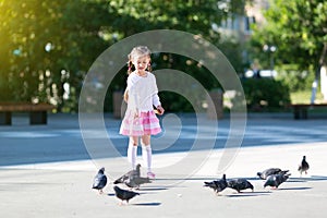 A little girl feeds pigeons.