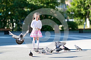 A little girl feeds pigeons.