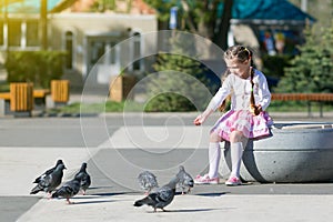 A little girl feeds pigeons.