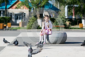 A little girl feeds pigeons.