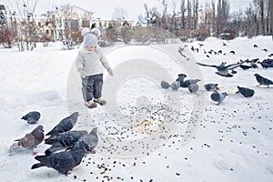 Little girl feeds pigeons in winter.