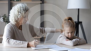 Little girl feel unmotivated doing homework with grandparent