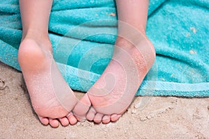 Little girl feet on a beach towel