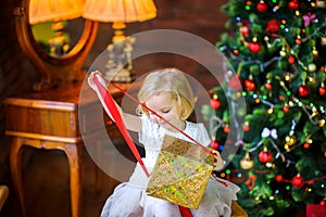 Little girl in a festive dress opens a gift