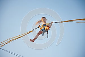 Little girl flies on elastic bands and jumps on a trampoline