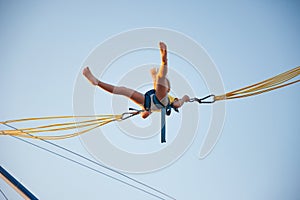 Little girl flies on elastic bands and jumps on a trampoline