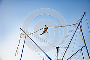 Little girl flies on elastic bands and jumps on a trampoline