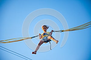 Little girl flies on elastic bands and jumps on a trampoline