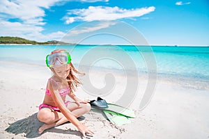 Little girl with flippers and goggles for snorkling on the beach