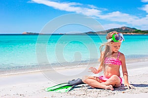 Little girl with flippers and goggles for snorkling on the beach