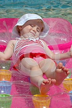 The little girl floats on an inflatable mattress