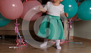little girl on the floor in the room next to the balloons, first birthday, celebrate. one year old blue and pink balls with butter