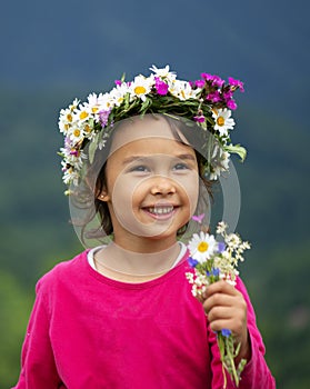 little girl with flower crown smiling and having fun on meadow