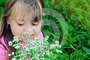 Little girl with flowing hair sniffs wildflowers.