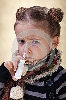 Little girl with the flu using nasal spray