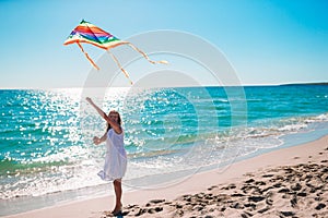 Little girl flying a kite on beach at sunset