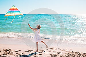 Little girl flying a kite on beach at sunset