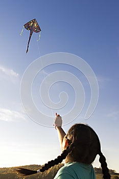 Little girl flying a kite in the sky.