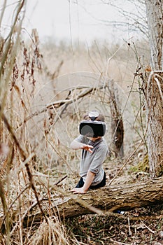 Little girl in a forest is having fun while using some VR headsets outdoor