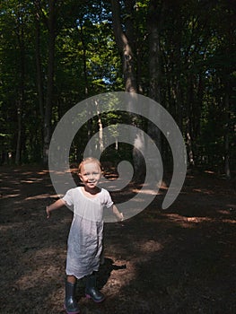 Little girl into the forest smiling and playing