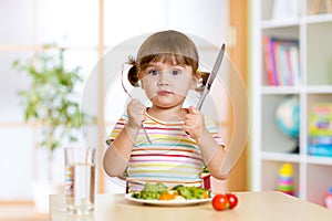 Little girl with fork and knife ready to eat