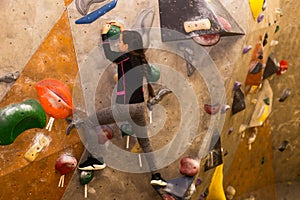 Little girl free climbing on artificial wall in gym, bouldering