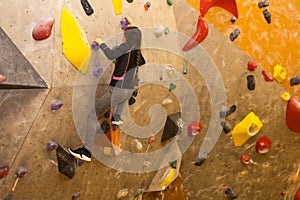 Little girl free climbing on artificial wall in gym, bouldering