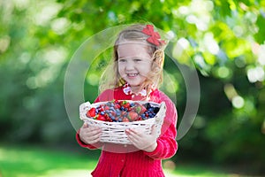 Little girl with fresh berries in a basket