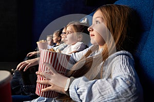 Little girl with friends sitting in cinema.