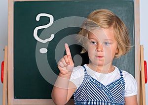Little girl in front of black board with forefinger up