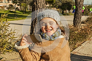 Little girl with funny kiss face and grey bonnet taking a selfie