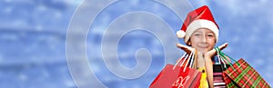 Little girl in fur-cap with shopping bags on blue background. Christmas