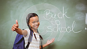 Little girl gesturing thumbs up in classroom