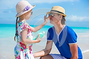 Little girl gets sun cream on her dad's nose