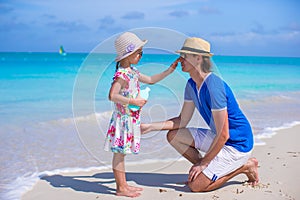 Little girl gets sun cream on her father's nose