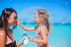 Little girl gets sun cream on her mother's nose