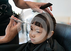 Little girl getting haircut by hairdresser at the barbershop